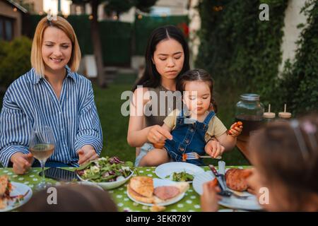 Famille multi-ethnique et amis appréciant le dîner barbecue en plein air Banque D'Images