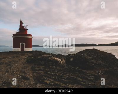 L'emblématique phare rouge vif de Punta Robaleira se trouve sur les falaises rocheuses escarpées de Costa da Vela, Cangas, Galice, Espagne. Océan Atlantique Banque D'Images
