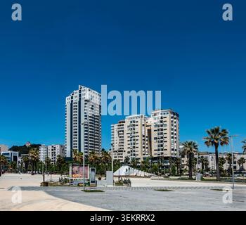 Les immeubles d'appartements modernes et les palmiers se dressent le long d'une large place publique sous un ciel bleu profond clair à Durres, en Albanie. Banque D'Images