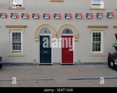 Deux portes d'entrée colorées sur une façade de maison traditionnelle à Halesowen, West Midlands Royaume-Uni avec des banderoles décoratives et des détails architecturaux Banque D'Images