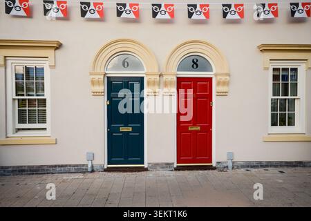 Deux portes d'entrée colorées sur une façade de maison traditionnelle à Halesowen, West Midlands Royaume-Uni avec des banderoles décoratives et des détails architecturaux Banque D'Images