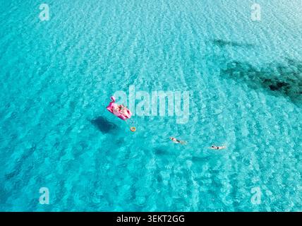 Vue aérienne des personnes se relaxant sur flamant rose gonflable en mer Banque D'Images
