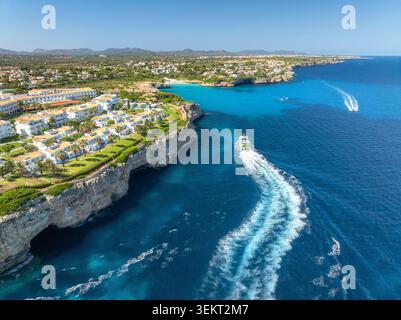 Vue aérienne d'une station balnéaire blanche avec villas, bateau, mer bleue Banque D'Images