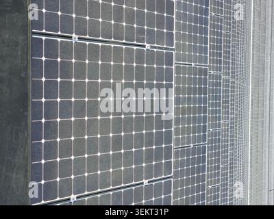 Les panneaux photovoltaïques couvrent l'extérieur du bâtiment moderne en rangées répétées. Énergie solaire, énergies renouvelables et architecture durable Banque D'Images