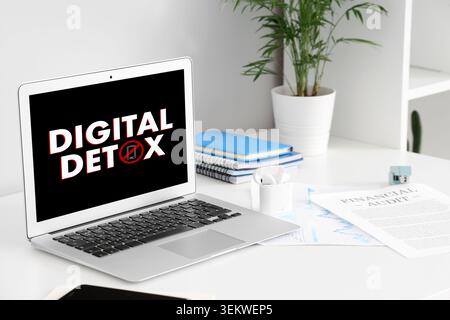 concept de détox numérique sur l'écran d'ordinateur portable dans l'espace de travail moderne de bureau à domicile avec symbole de smartphone, bureau propre, documents d'audit financier, écouteurs sans fil Banque D'Images