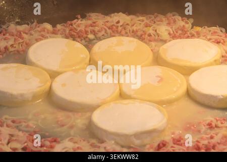 Cuisson de tartiflette, un plat traditionnel français de pommes de terre festonnées, bacon et fromage, dans un grand chaudron Banque D'Images