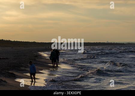 Île de Sobiszewska, POLOGNE-02 SEPTEMBRE 2024 : les gens marchant le long de la plage de sable au coucher du soleil, profitant de la soirée paisible avec le rouleau de vagues de mousse de l'océan Banque D'Images