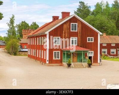 Sala, Suède - 08.07.2022 : Grand bâtiment historique Falu en bois rouge avec une véranda verte et un toit en tuiles dans une cour de gravier Banque D'Images
