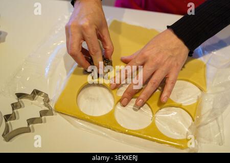 Mains utilisant des emporte-pièces sur la pâte à biscuits roulée pour le dessert maison Banque D'Images