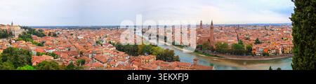 Vérone, Italie - 04.10.2021 : large panorama aérien de l'Adige qui coule devant l'architecture ancienne, les tours d'église et la verdure luxuriante en Italie Banque D'Images
