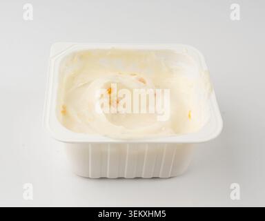Tasse de yogourt isolée, yaourt avec des morceaux de fruits orange dans un pot en plastique, récipient de pudding de lait, petit paquet de produits laitiers sur fond blanc Banque D'Images