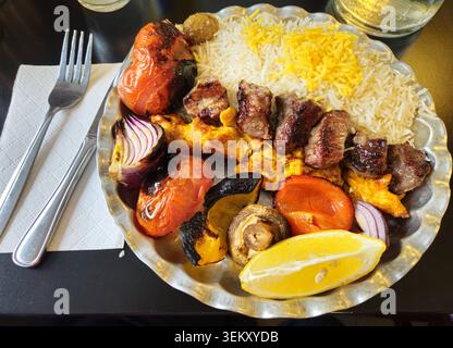 Assiette de kebab de grillades persanes multicolores avec brochettes de bœuf et de poulet grillées, tomates et oignons carbonisés, riz basmati safran et citron W. Banque D'Images