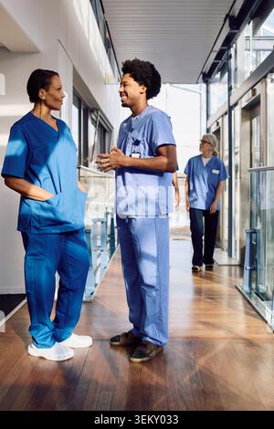 Infirmier parlant avec une femme médecin senior debout dans le couloir de l'hôpital Banque D'Images