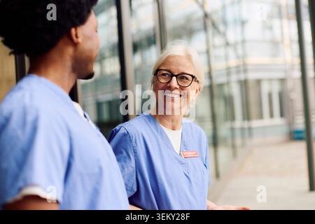 Médecin de sexe féminin principal passant du temps libre avec un collègue pendant la pause à l'extérieur du bâtiment de l'hôpital Banque D'Images
