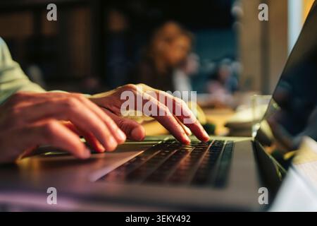 Gros plan de l'homme d'affaires tapant le courrier sur ordinateur portable tout en travaillant à l'espace de coworking Banque D'Images