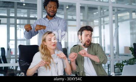 Active Happy équipe d'affaires multiethnique dansant répétant le même mouvement avec des mains chantant célébrant le travail d'équipe dansant écouter de la musique ensemble amusant Banque D'Images
