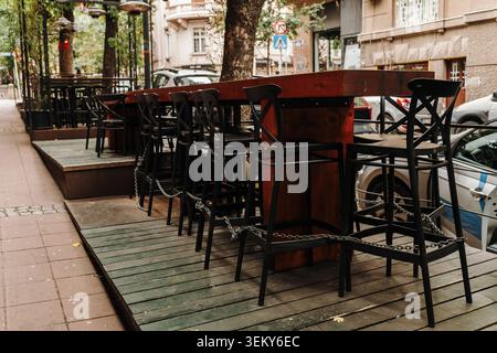 Tables hautes et chaises de bar disposées sur une terrasse extérieure à côté d'une rue urbaine. Concept d'hospitalité et de style de vie urbain pour les repas et les interactions sociales Banque D'Images