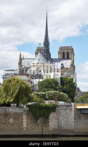 Paris, France - 11 mai 2026 : côté est de la cathédrale notre-Dame de Paris avec échafaudages, arbres et berges de la Seine visibles au premier plan Banque D'Images