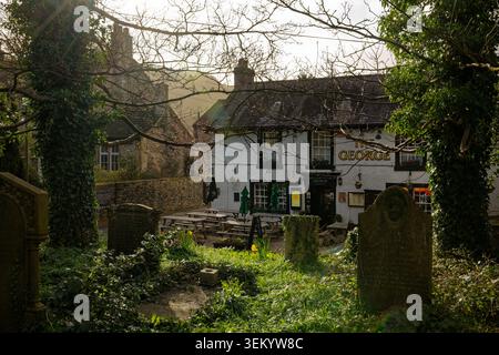 Un pub appelé The George dans un village rural en face d'un cimetière avec des tombes, Castleton, Peak District, Derbyshire. Banque D'Images