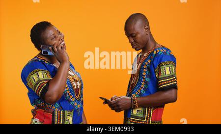 Les Afro-américains répondant à un appel téléphonique sur la caméra, parlant à des amis ou à la famille sur la ligne téléphonique en studio. Couple marié discutant joyeusement sur smartphone, communication à distance. Banque D'Images