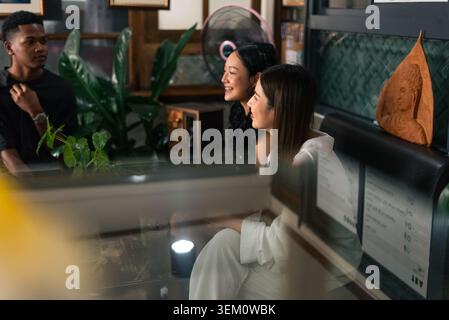 Jeunes amis divers appréciant la conversation ensemble dans une cafétéria confortable Banque D'Images