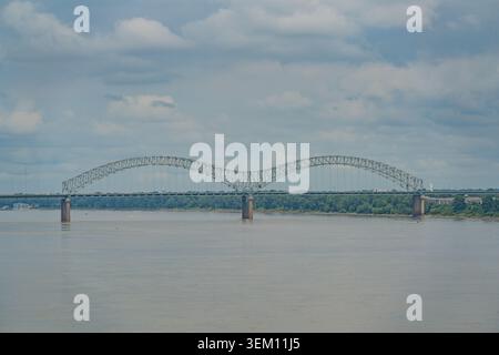 Une vue large du pont Hercules Harbor qui enjambe le fleuve Mississippi avec un bateau de croisière visible au loin sous un ciel nuageux. Banque D'Images