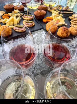 Deux échantillons de vin blanc et deux échantillons de vin rouge servis dans des verres sans pied, servis avec des planches de charcuterie sur un patio extérieur. Banque D'Images