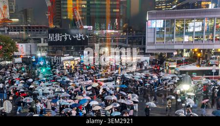 Des foules de piétons porteurs de parapluies traversent Shibuya Scramble Crossing sous la pluie la nuit, Tokyo, Japon Banque D'Images