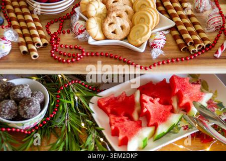 Présentoir de service à deux niveaux comprenant des biscuits sablés étoilés, des gaufrettes au chocolat, des truffes et des tranches de pastèque en forme de sapin de noël. Banque D'Images