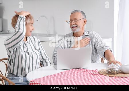 Couple sourd mature muet utilisant la langue des signes à table dans la cuisine Banque D'Images
