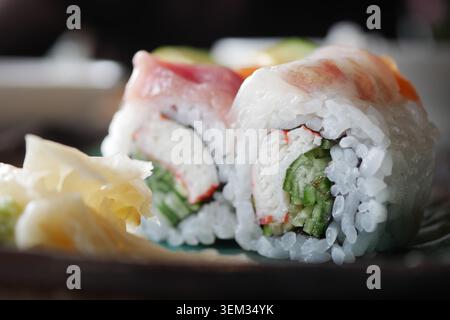 Plat à sushi servi sur une assiette sombre avec des garnitures Banque D'Images