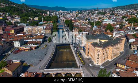 Vue aérienne par drone du bâtiment historique de Vijecnica et de la rivière Miljacka qui traverse le paysage urbain de Sarajevo Banque D'Images