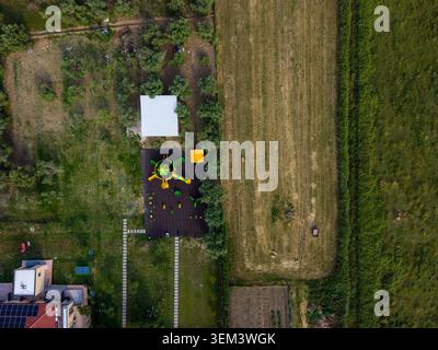 Vue aérienne d'une aire de jeux colorée pour enfants avec toboggans jaunes à côté d'un bâtiment blanc et de champs verdoyants Zvernec, comté de Vlore, Albanie. Banque D'Images