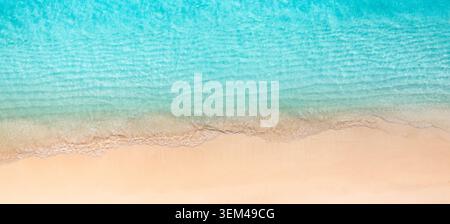 Vue aérienne par le dessus de la mer turquoise rencontrant une plage tropicale de sable. Gradient d'eau bleu clair minimal. Fond de paradis de voyage d'été avec espace de copie Banque D'Images