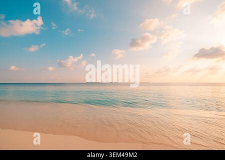 Couchant pastel sur une mer calme et une plage de sable lisse, des nuages doux brillant au-dessus d'un horizon tranquille, une soirée rêveuse et paisible sur une côte tropicale pittoresque. Bien-être Banque D'Images