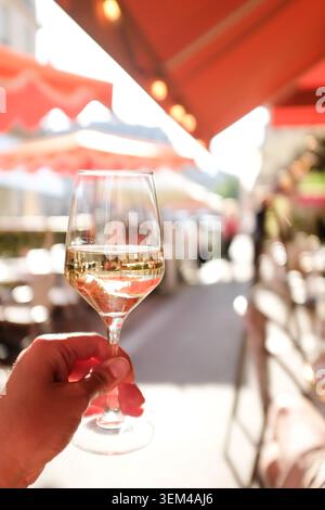 Personne tenant du vin blanc dans un café de trottoir ensoleillé à Paris Banque D'Images
