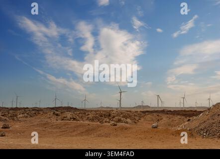 Ferme éolienne à grande échelle générant de l'énergie propre renouvelable sur un terrain désertique aride avec un sol rocheux exposé et une végétation clairsemée sous-jacente Banque D'Images