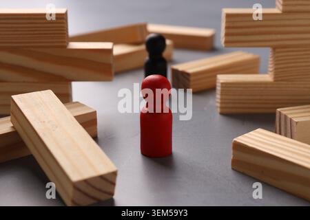 Mur en bois effondré fait de blocs et de figures humaines sur la table grise, gros plan. Surmonter les obstacles Banque D'Images