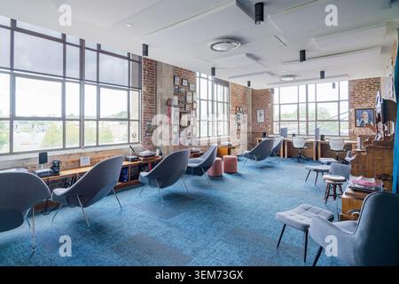 Memphis, États-Unis, 24 MAI 2026 - Intérieur spacieux d'un espace de travail contemporain avec moquette bleue, chaises longues grises, brique apparente Banque D'Images