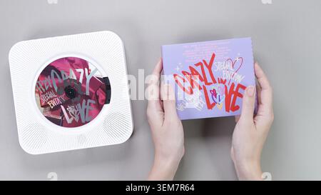 Les mains des fans ont tenu 1st albums de musique du groupe k-pop Itzy CRAZY DANS L'AMOUR sur fond gris. Pink Music CD dans un lecteur rétro blanc. Groupe de filles sud-coréennes I Banque D'Images