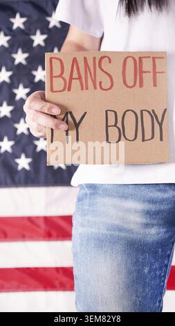 Une femme portant un panneau interdit le drapeau américain de mon corps en arrière-plan. Protestation contre la loi anti-avortement. Grève des femmes. Liberté des droits des femmes Banque D'Images