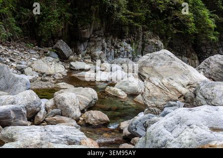 Lit de rivière Sanzhanxi avec de grands rochers de marbre à Taroko, Taiwan. L'eau claire coule entre les pierres. La forêt verte couvre des falaises abruptes. Banque D'Images