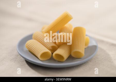 Sécher les pâtes rigatoni sur une soucoupe avant de les cuire Banque D'Images