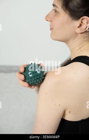 Femme utilisant la boule de massage pour le soulagement de la douleur de l'épaule Banque D'Images