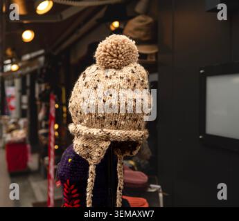 Bonnet d'hiver à rabat en maille confortable avec pompon exposé dans un Street Market Shop Banque D'Images