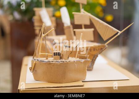 Modèles de navires en carton faits à la main avec des mâts en bois debout sur une feuille de papier lors d'une exposition en plein air, des projets de recyclage créatifs et tôt e Banque D'Images