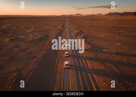 Convoi aérien de 4x4 blancs sur route de gravier en Namibie au coucher du soleil Banque D'Images