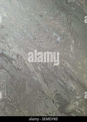 Le fond montre un tissu gris argenté métallisé. Il a une texture avec des motifs ondulés et une surface brillante. Ce tissu peut être utilisé dans diverses conceptions Banque D'Images