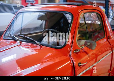 Un gros plan capture une voiture vintage rouge éclatante présentant des caractéristiques extérieures polies. Parmi les caractéristiques principales, mentionnons le pare-brise, les essuie-glaces, les rétroviseurs extérieurs, les poignées de porte Banque D'Images
