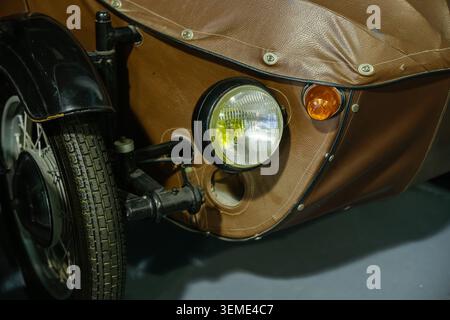 Vue rapprochée détaillée d'un side-car de moto vintage avec revêtement texturé brun et phare chromé. Petit voyant orange et une partie de Banque D'Images